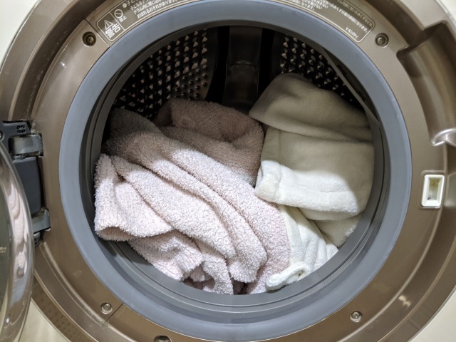 カシウエアを洗濯機で洗っている様子。1枚がカシウエア、もう１枚が同色のバスローブ。ドラム式洗濯機の中に入っている。