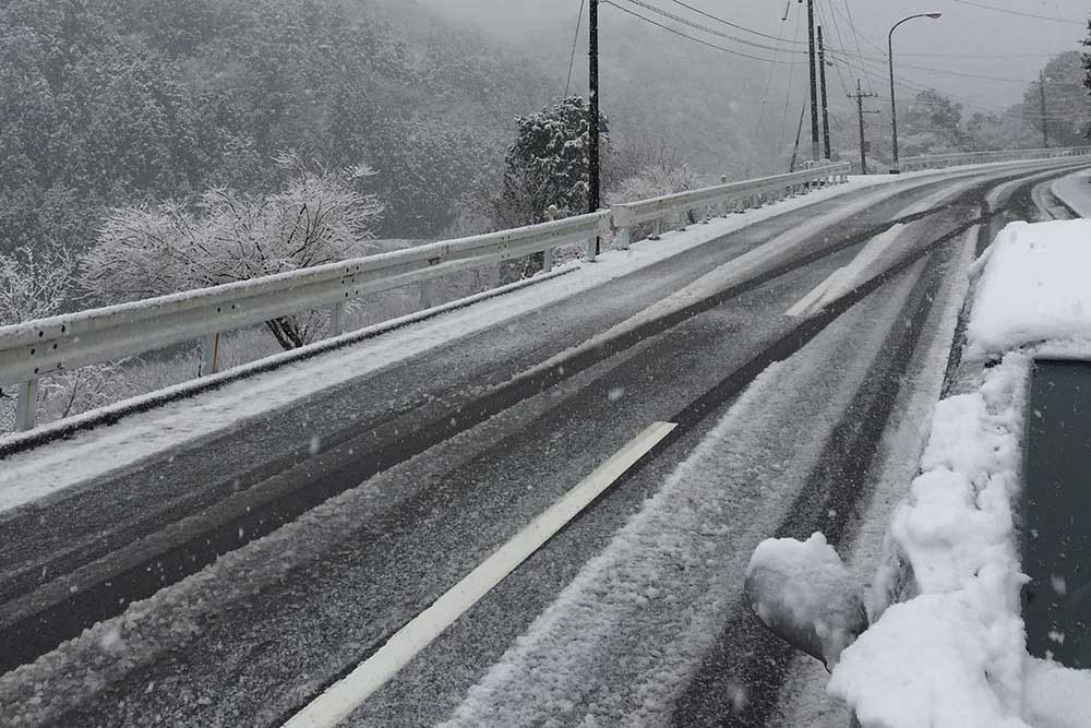 雪が積もった冬の道路とクルマ