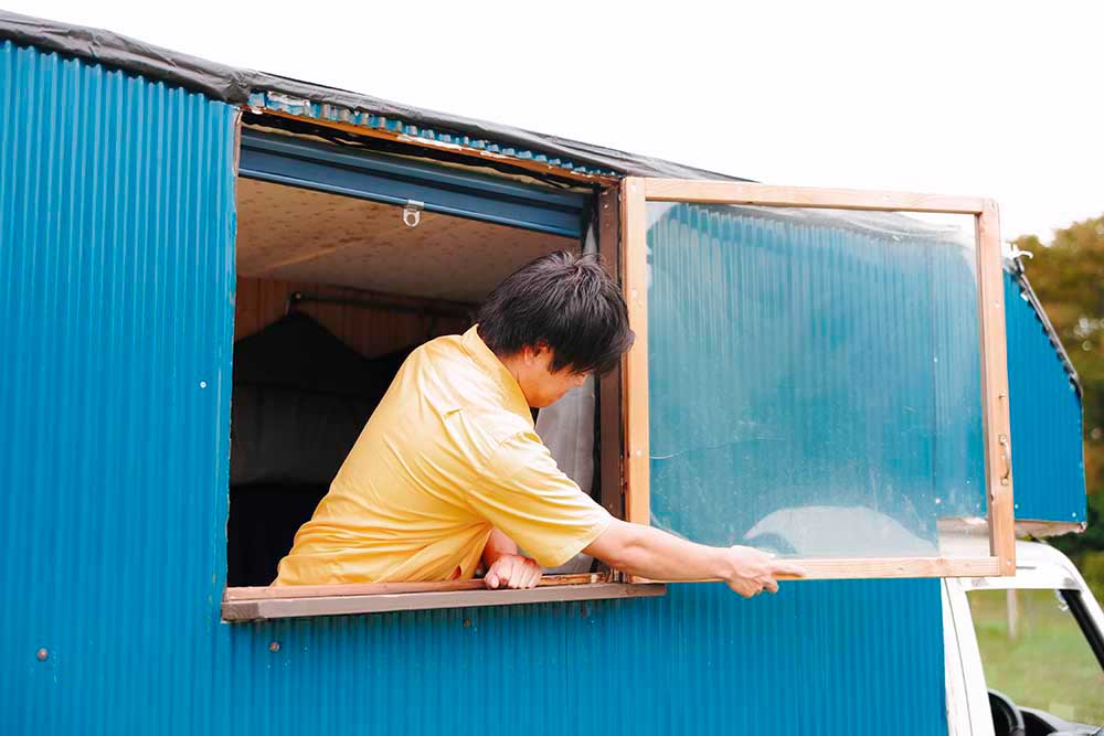 軽トラキャンピングカーの窓をあけるはっしーはっぴーさん