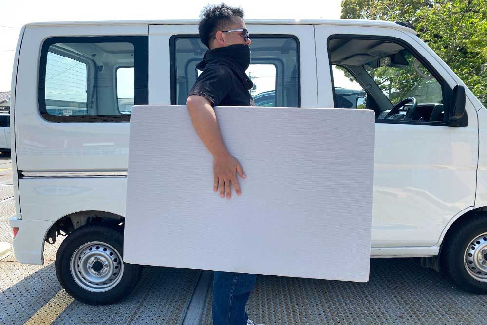 トヨタ ピクシスバンの前で高反発3つ折りマットレスを持つ男性