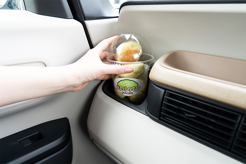 車内のドリンクホルダーから、ぽるとがるのミニメロンパンを取り出す様子