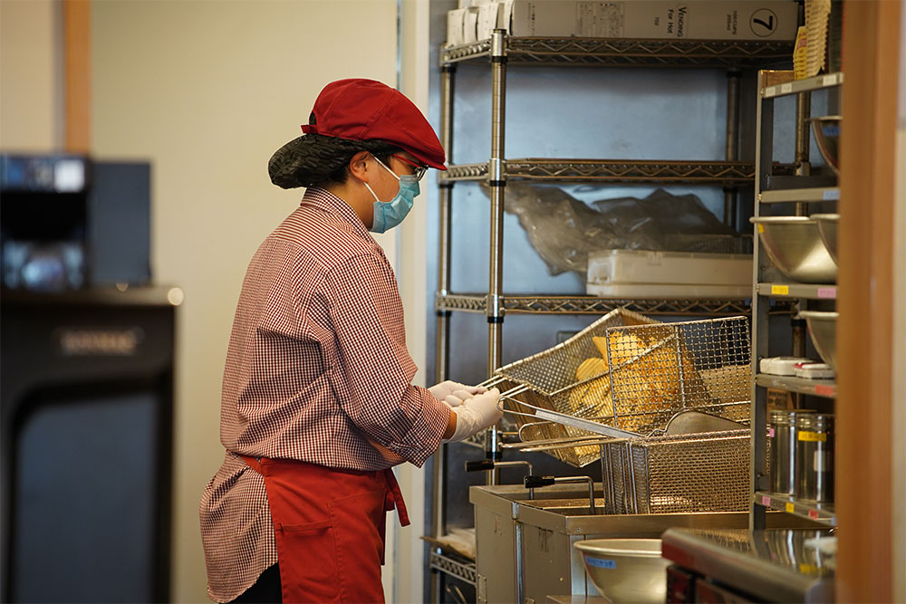カルビーキッチンの厨房で、店員さんがポテトチップスを揚げている様子