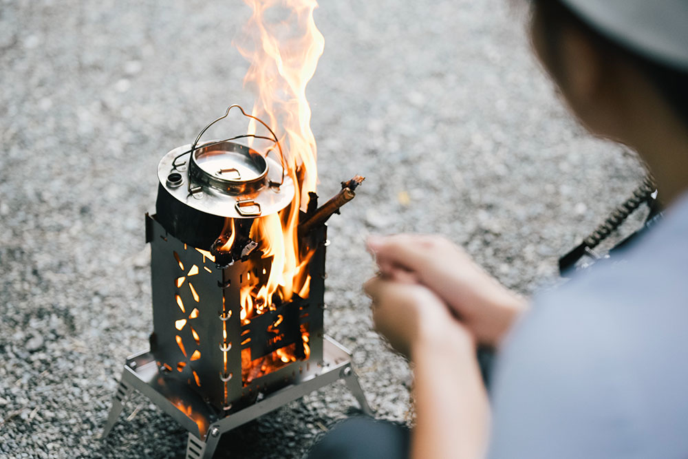 やかんを直火にかけながら焚き火にあたるまほさん
