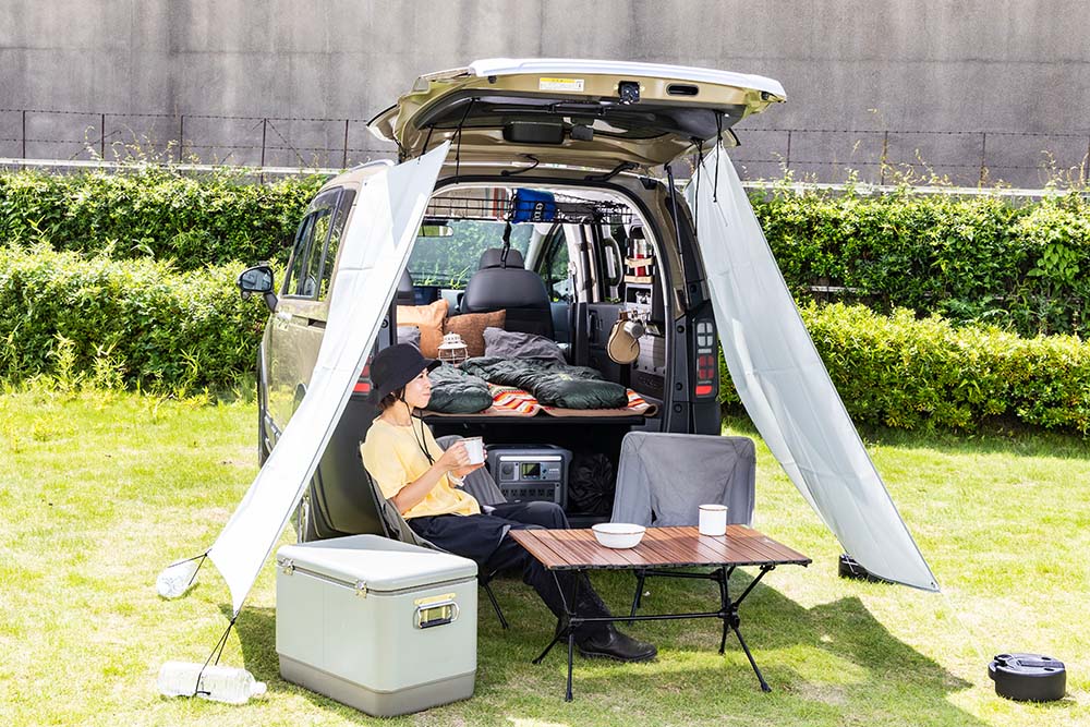 純正アクセサリーのテールゲートタープを取り付けたフリード クロスターの下でくつろぐ女性