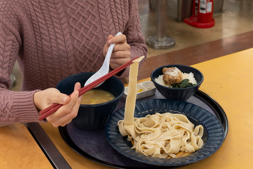 彩の国タマシャモの鶏塩つけ汁うどんを食べる様子