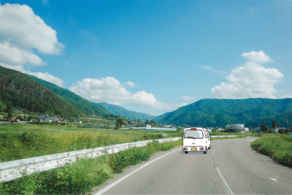 長野の山々が見える街道を進む白くま