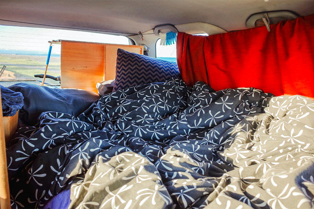 寝床と赤いカーテンが設えられたグランディス車内の様子