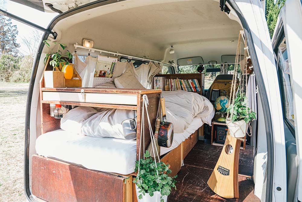 ベッドや棚が設えられ、観葉植物やギターなどで彩られた車内空間