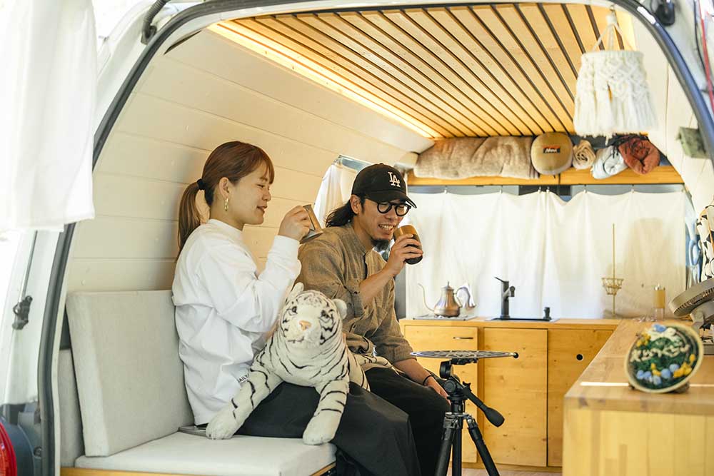 ソファモードの車内でコーヒーを飲む２人