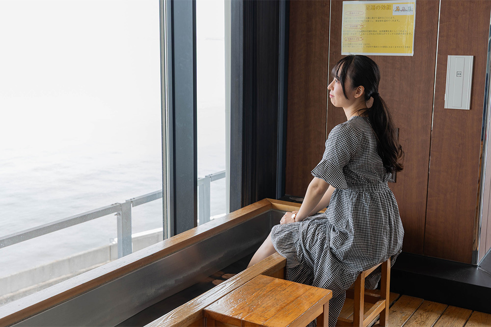 足ゆに足をつけて外を見るライター