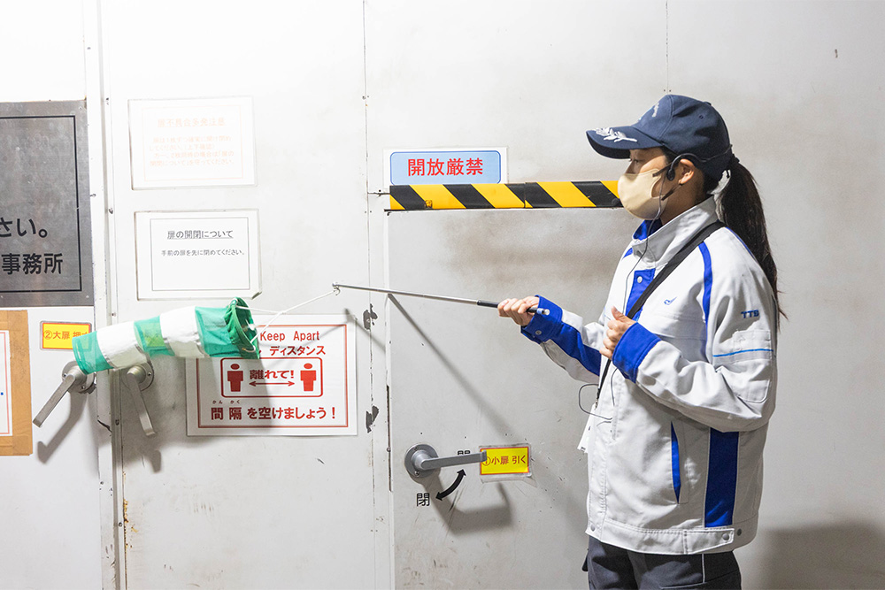 緊急避難通路の扉の風圧を見せるガイドの様子