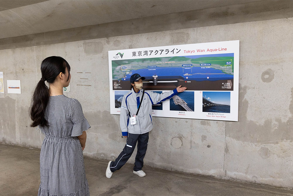 東京湾アクアラインの構造についてパネルを使って説明するガイドさん