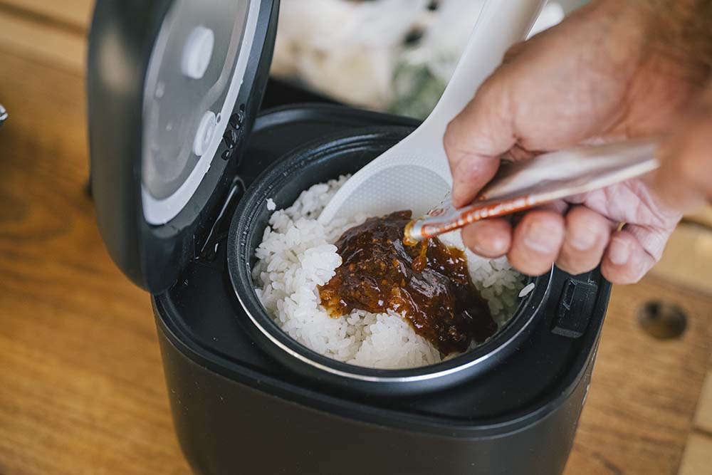 炊き上がったご飯に混ぜごはんの素を入れている様子