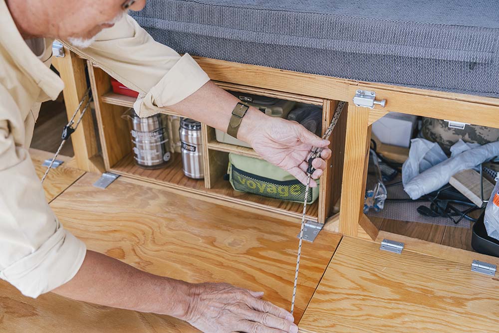 テーブルに付いたベッド台から伸びるロープを調整している様子