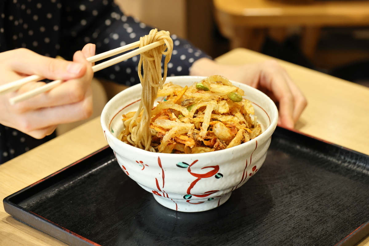 季節野菜のかき揚げそばを食べるシーン