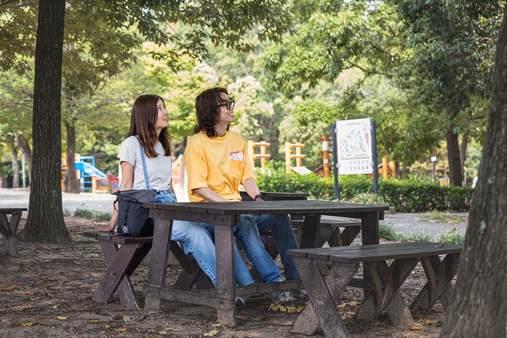 岩ケ池公園のベンチでくつろぐ男女