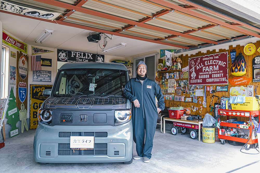 ガレージ内で愛車N-VAN e:と共に笑顔で写るカーミットさん