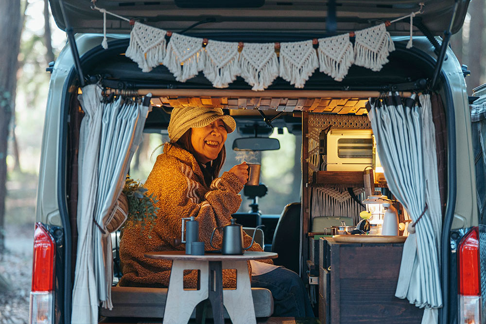 車内でコーヒーを飲みながら笑顔を見せるななたびさん