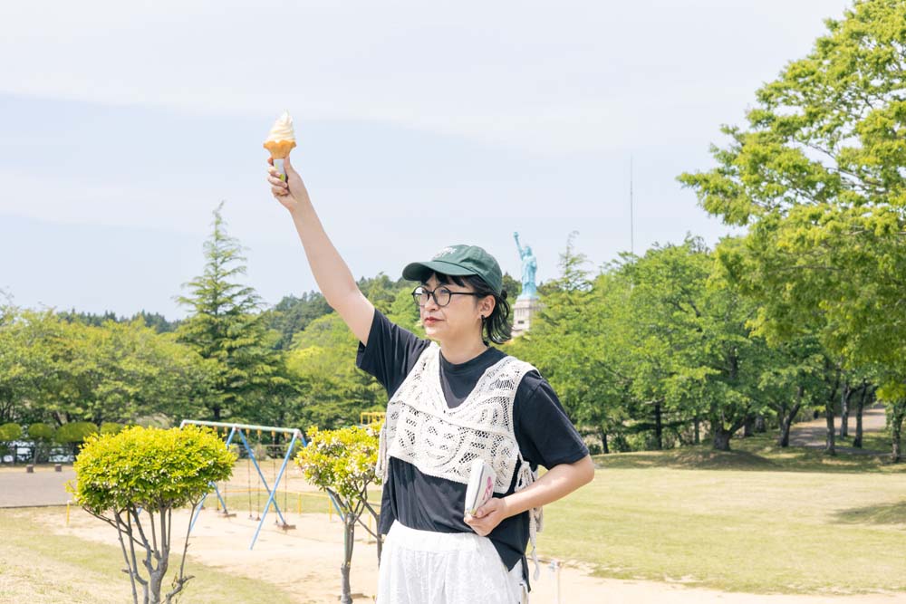 ソフトクリームをもって自由の女神になりきる栗本さん