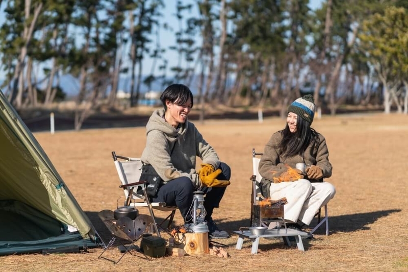 キャンプ場で椅子を並べて話す野外のもりこさん夫婦