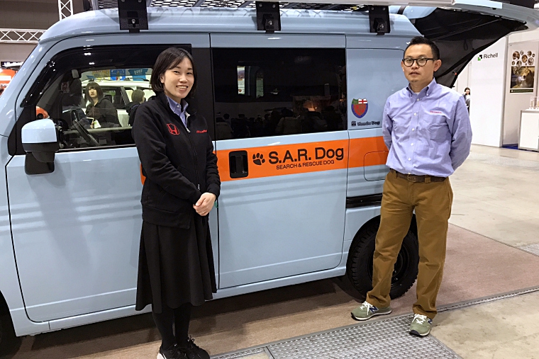 Honda Dogコーナーに展示されている車「S.A.R. Dog Concept」の前に立つホンダアクセス 商品企画部のデザイナーである加藤 智久さん（右）と、企画担当の蓑和（みのわ） 佳苗さん（左）