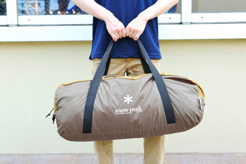 テント（タープは入ってない）が収納されたバックを持つ様子