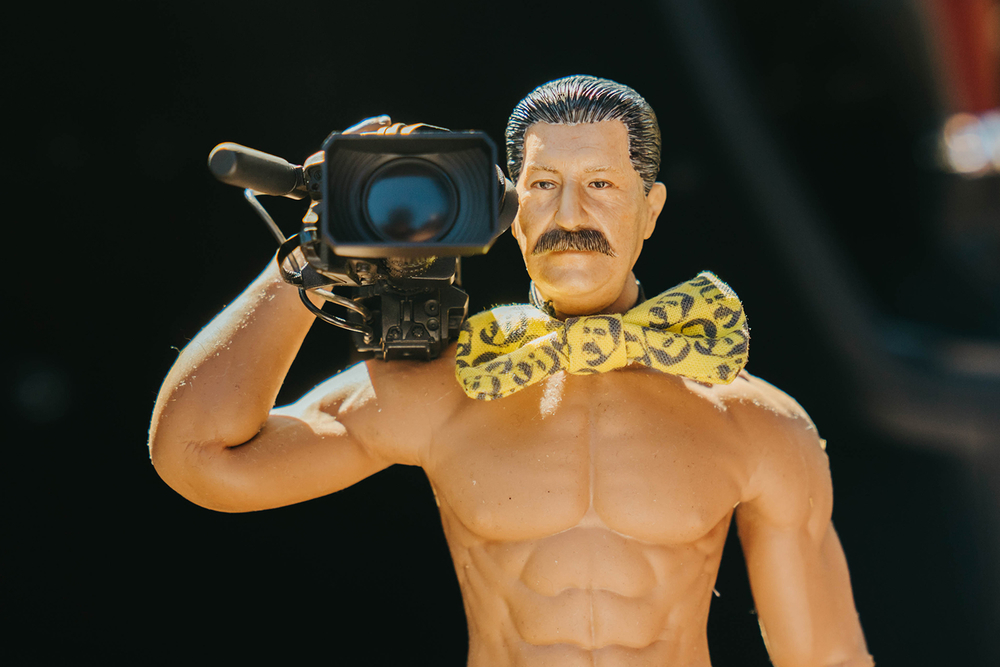 裸に蝶ネクタイで、カメラを肩にかついだヨシダさん