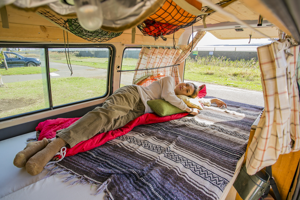 愛車「サンシー号」のベッドに寝そべるYURIEさん　