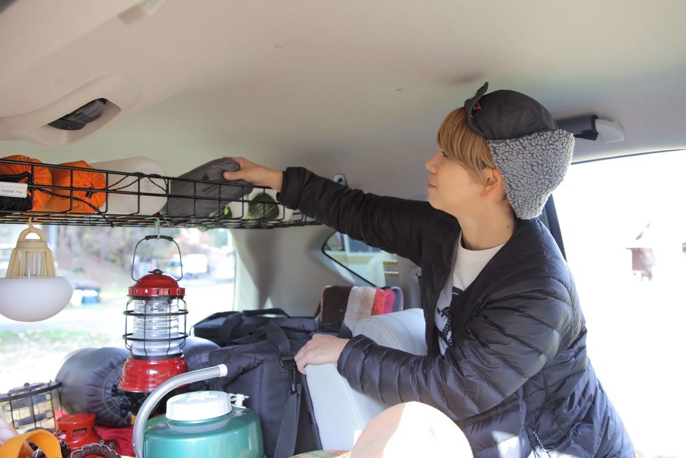 ルーフラックにキャンプ用品収納をする美加さん