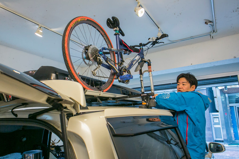 小澤さんがマウンテンバイクの前輪を外して屋根のキャリアベースに固定している