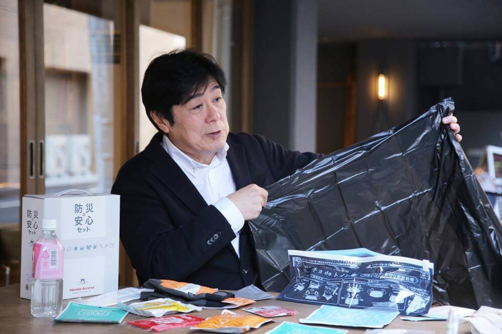 ポンチョdeトイレの目隠し用ポンチョを広げる和田さん