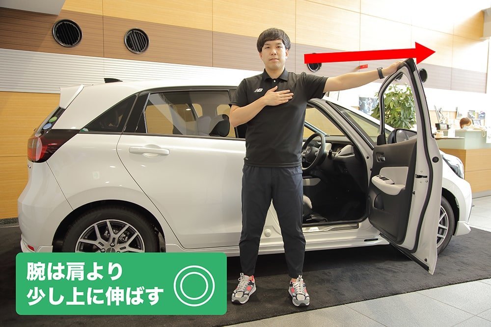 胸に手を当て、腕を伸ばしてドアに手を当てるオガトレの尾形 竜之介さん