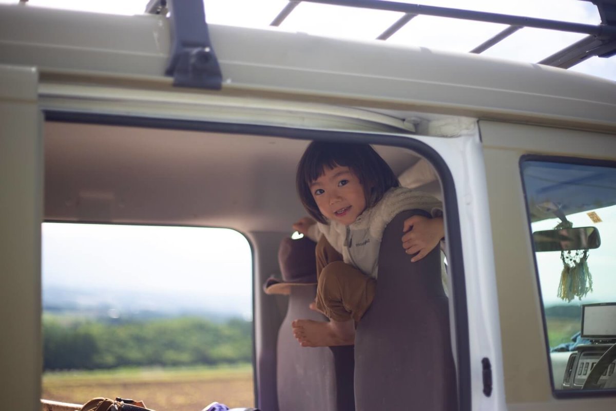 ４２ 　レトロなカスタムカー。キャンプコーディネーターの三沢真実さん。2018年夏、車中泊の旅の途中、北海道にて。息子のアリくんがシートのあいだから顔を出している