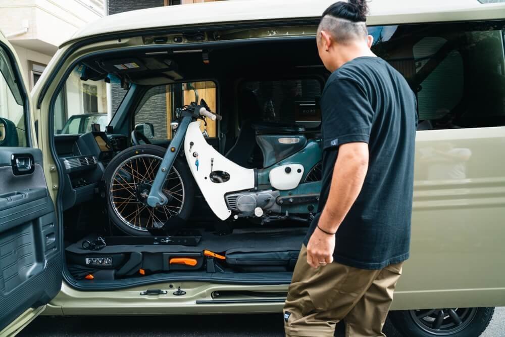 トランポ仕様にカスタムしたN-VANの車内に積み込まれたスーパーカブを見るオーナーの堀さん