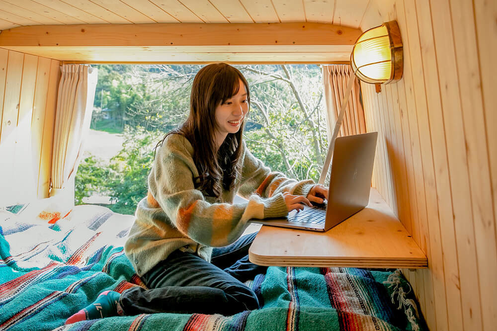 鈴木大地さんのメルセデス・ベンツのトランスポーターT1Nの車内で、テーブルに置いたパソコンを見る森さん