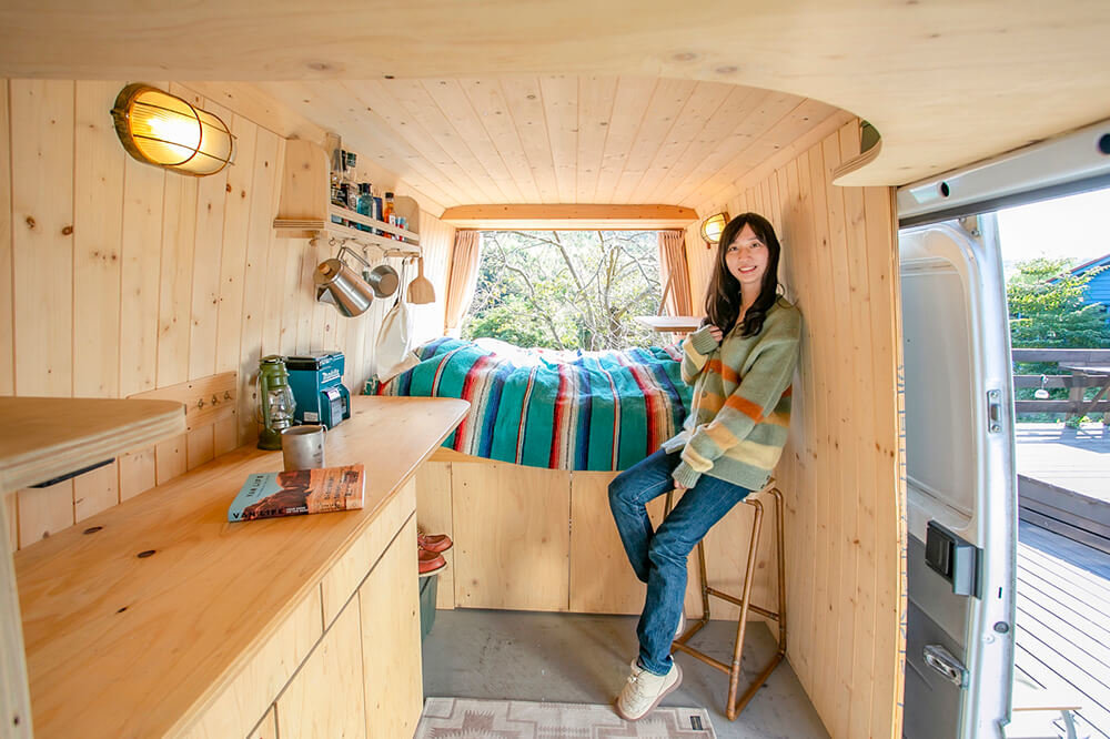 鈴木大地さんのメルセデス・ベンツのトランスポーターT1Nの車内で、スツールに座る森さん