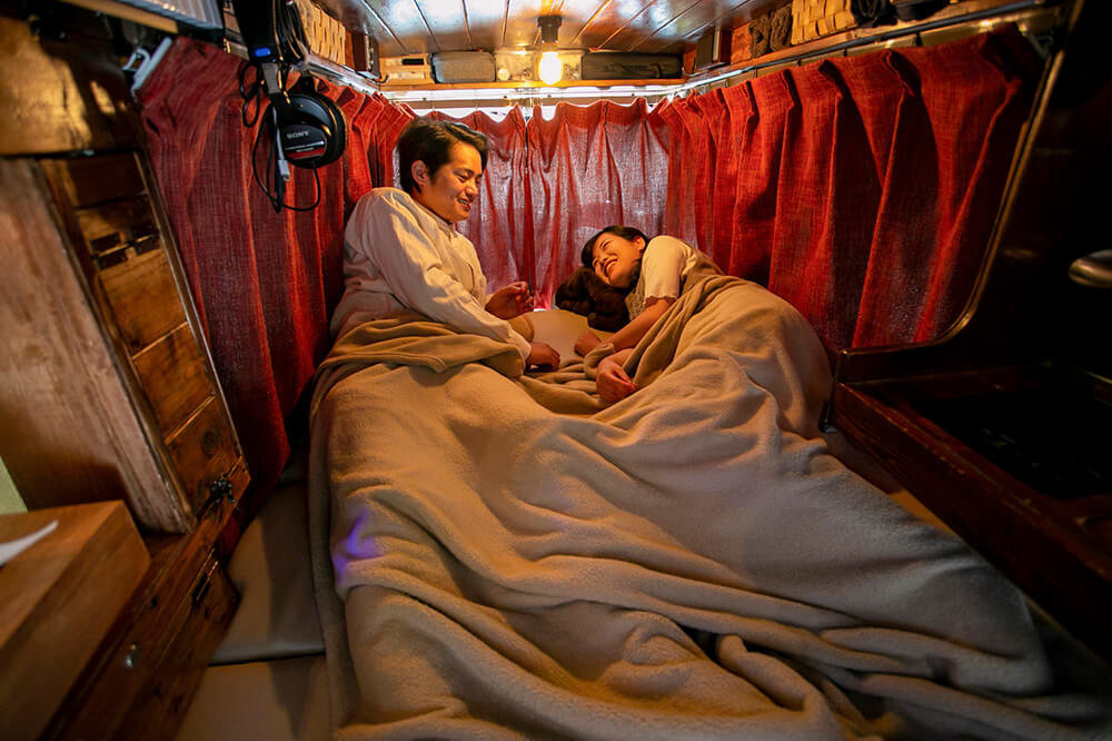 カーテンを閉めて、ふとんを敷き、夜、寝るときの様子を再現するあかねさんとはやとさん