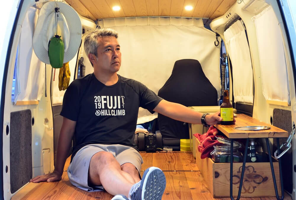 キャンピングカーに改造したハイゼットカーゴの車内で過ごす渡辺さん