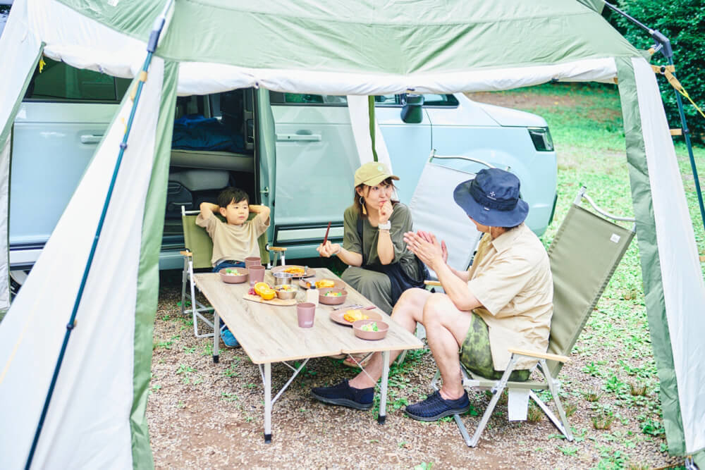 キャンプ場で食事を楽しみながら、家族団らんしているシーン