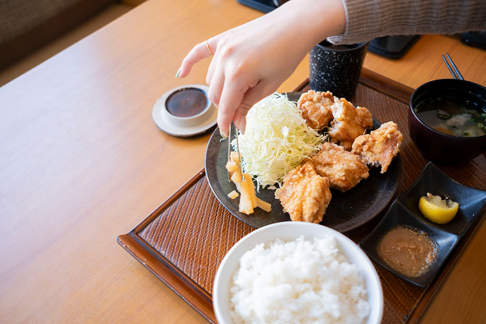 から好しにある大根のお漬物を皿にとる山口真央