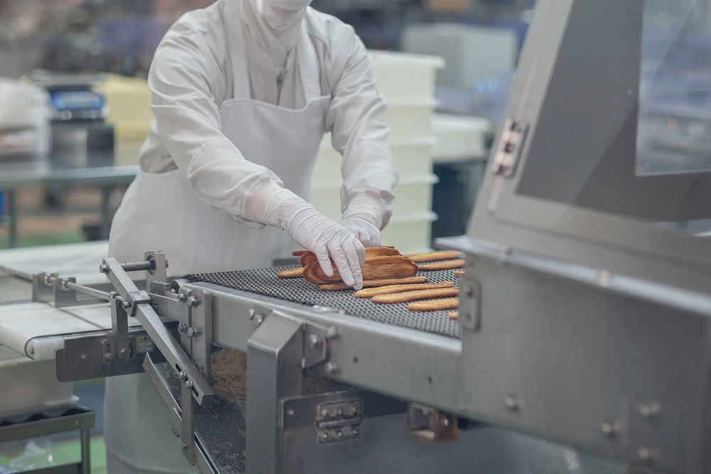 焼きすぎてしまったうなぎパイを人の手によって回収している