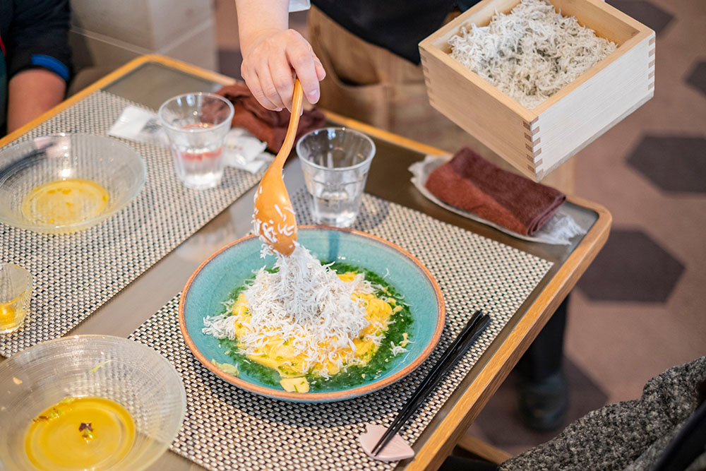 店員さんがオムライスにしらすをかけていく