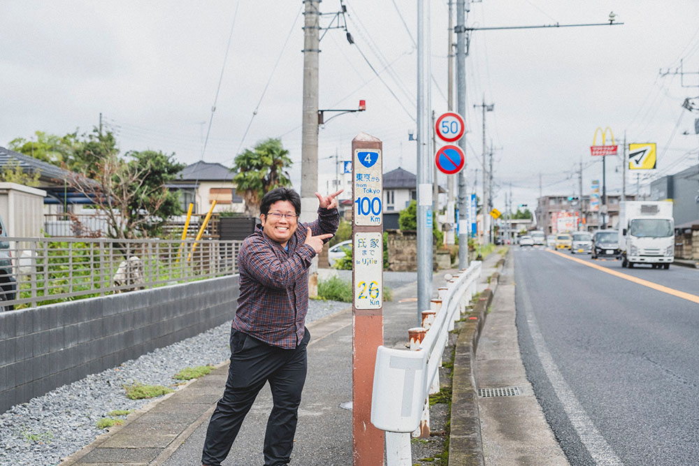 100kmポストの横でポーズをとる少年B