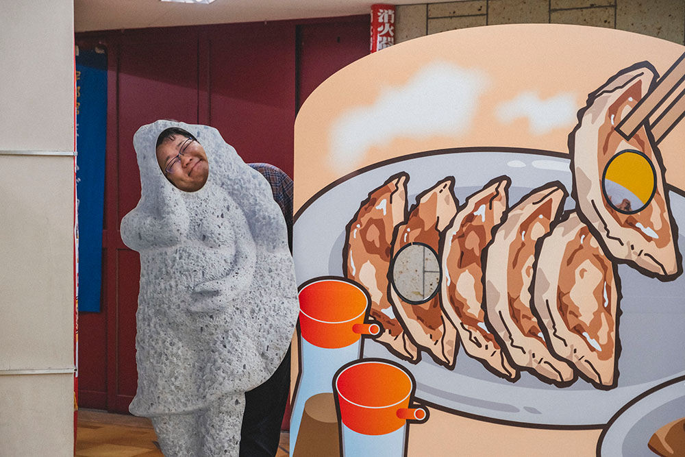 来らっせにある宇都宮餃子像顔出しパネルで写真を撮る少年Bさん