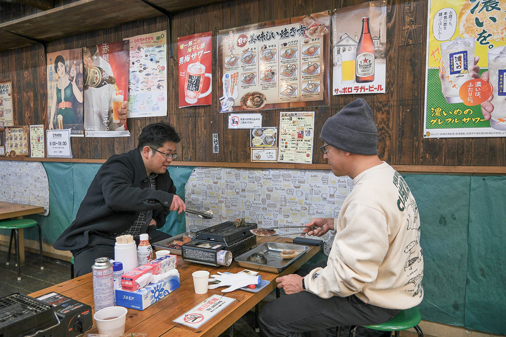 席について浜焼きを始める少年Bさんと杉本清隆さん