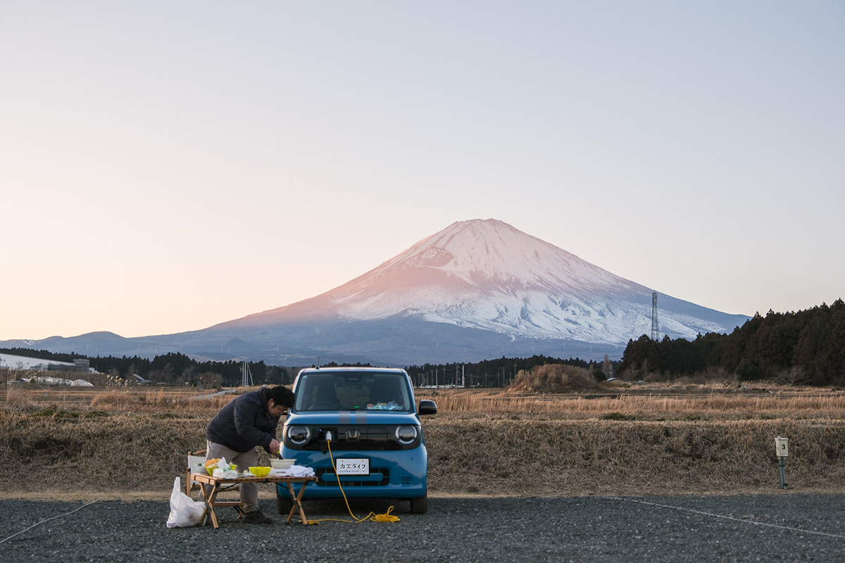 夕焼けに染まった富士山の下で調理をする少年B