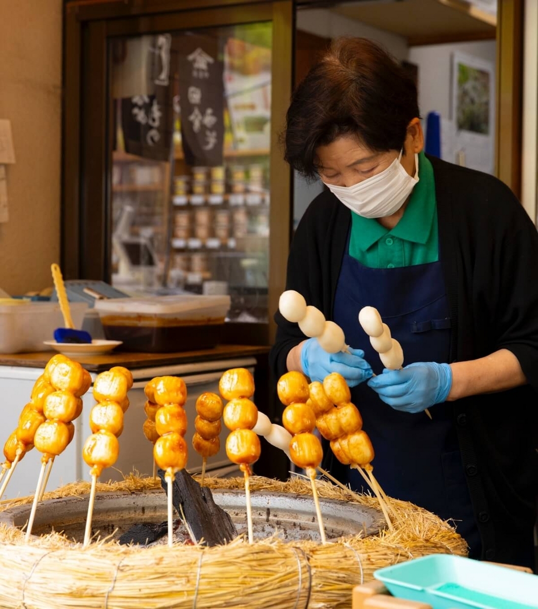 24_黄金だんごを炭火で焼いている女性