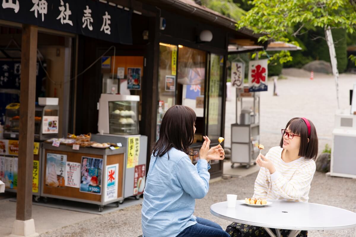 宝登山神社売店の前のテーブルで味噌ポテトを食べている女性たち