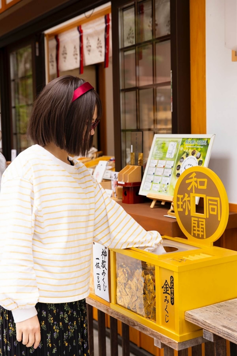 49_聖神社の金みくじを引く女性