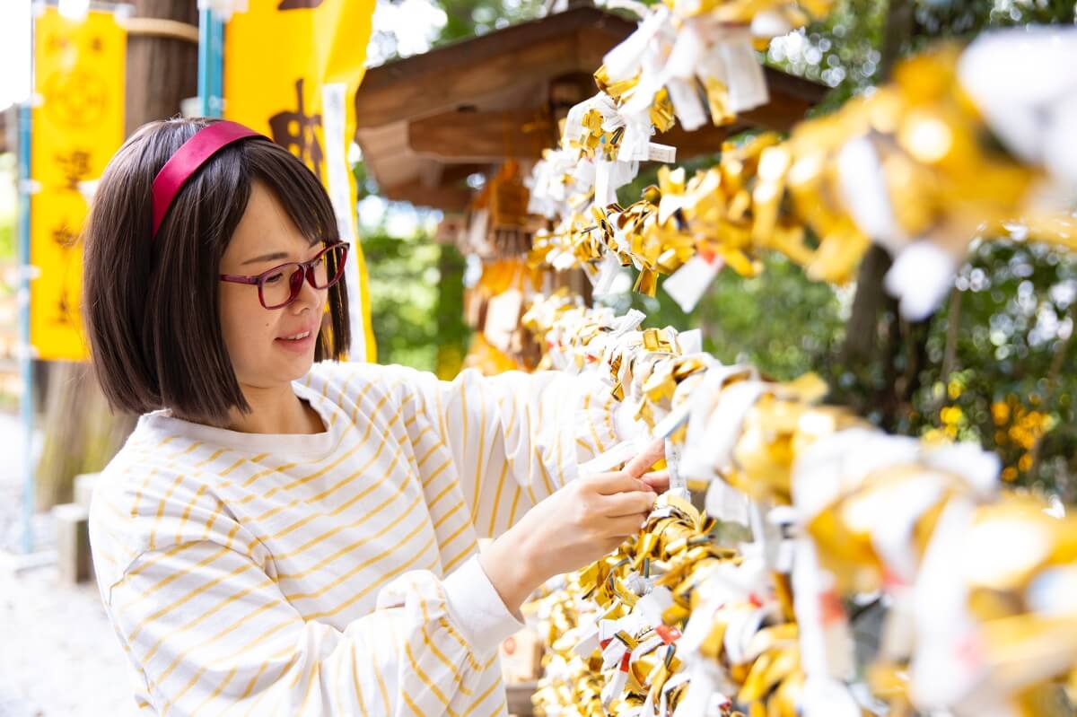 52_聖神社でおみくじを結ぶ女性